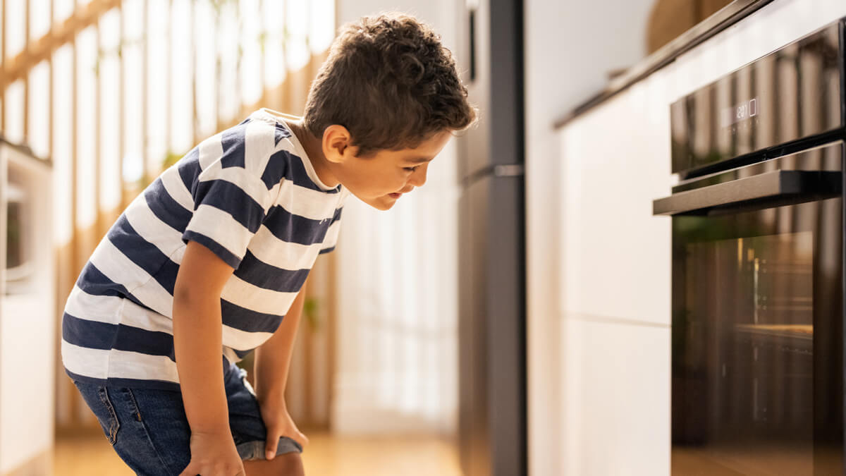 a happy child looking at an oven