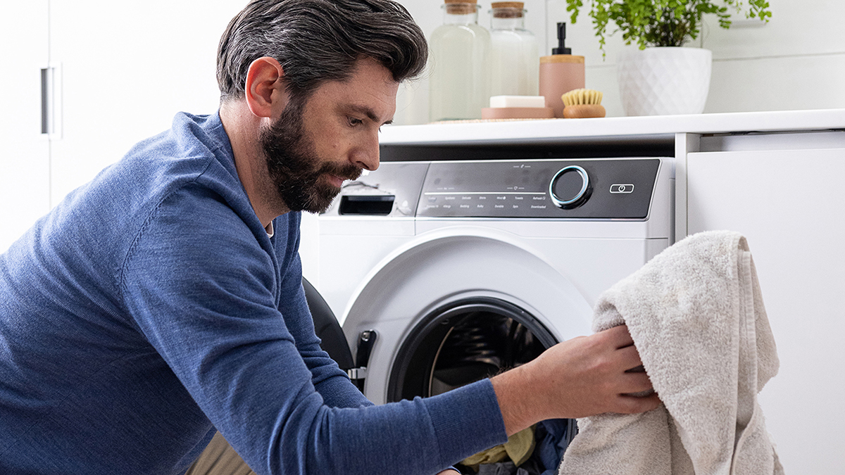 A man loading towels into a dryer