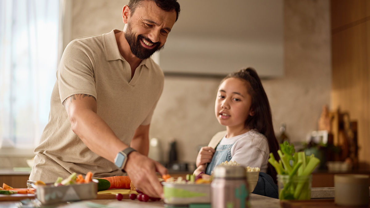 a father and daughter preparing food in the kitchen